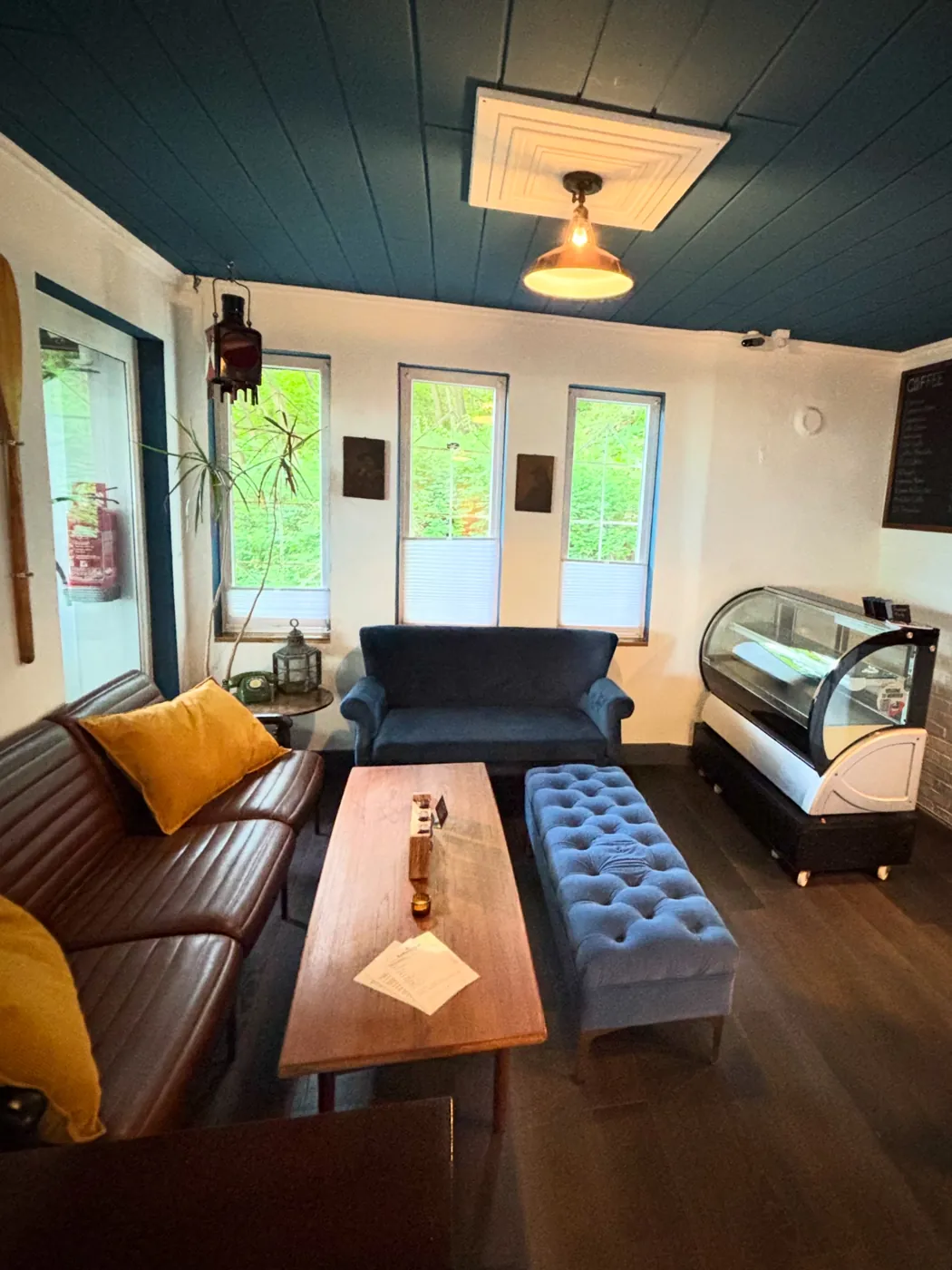 Lounge-Ecke mit Ledersofa, blauem Sofa und Kuchenvitrine